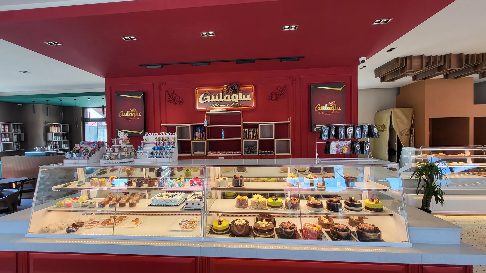 Kırmızı duvarlı salon, altın Güloğlu tabelası ve pasta vitrini